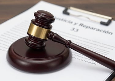 A photo of a legal gavel resting on a folder labeled 'Justicia y Reparación', symbolizing the organization's commitment to the Law 1448 of 2011.