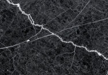 Close-up shot of a dark charcoal marble slab with striking white lightning-style veins, highlighting the premium quality and depth of the stone.