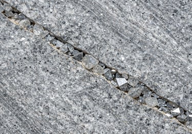 A high-resolution detail shot of a silver-grey granite slab with large crystalline structures, professional architectural photography style, reflecting timeless elegance.