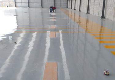 piso epóxico industrial con señalización de seguridad en nave de producción