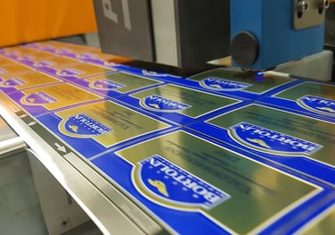 Industrial machine printing blue and gold Bortolin beverage labels on a high-speed production line.