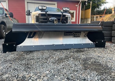 picture of the front of a white truck with a silver plow blade on it