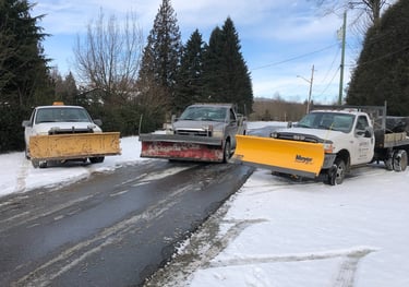 three plow trucks parked beside each other