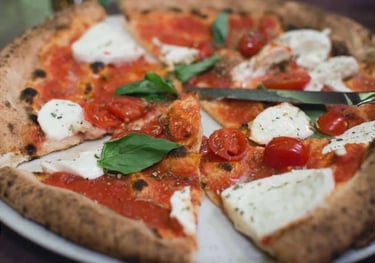 Pizza artisanale généreuse de chez PIZZ’ENTREPOTES servie dans l'ambiance indus du food court.