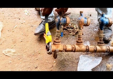 Plombier réparant un compteur d'eau principal et des tubes rouillés à la clé.