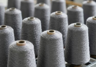 Industrial cones of high-tenacity yarn organized on a steel rack, showcasing the scale of manufacturing, featuring colors #1A202C and #95A5BB.