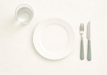 Farfurie goală văzută de sus, cu tacâmuri și un pahar cu apă, simbol al relației dificile cu alimentația