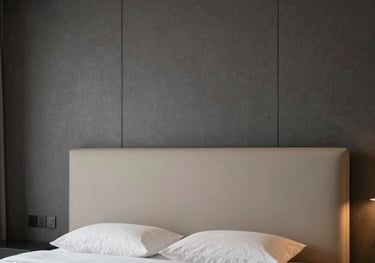 Detailed photography of a luxury bedroom interior in a Central Anatolian villa, showcasing a minimalist beige headboard, dark gray wall panels, and sophisticated ambient lighting.