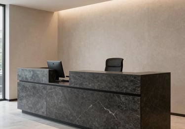 A professional and modern law office reception area in Ankara, featuring a dark gray stone desk, beige wall accents, and a minimalist architectural layout.