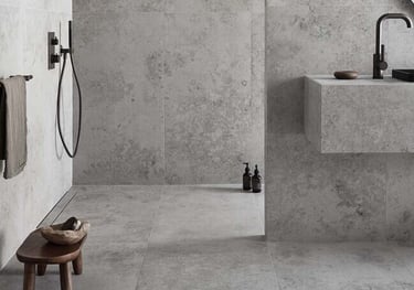 Modern minimalist bathroom featuring grey stone-effect tiles on walls and floors with black matte fixtures.