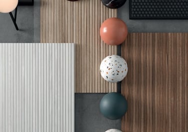 Flat lay of interior design samples featuring wood slat panels, marble spheres, and terrazzo textures.