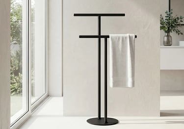 Freestanding matte black towel rack with a white towel in a modern minimalist bathroom.