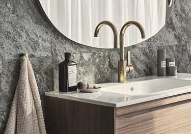 Modern bathroom vanity with a gold faucet, white sink, and grey marble tile backsplash.