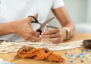 Manos cortando cordón de algodón color crema para macramé.
