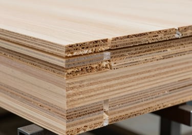 A close-up photograph of a Cross Laminated Timber panel section in a professional Central European factory. The precise layers of wood and high-tech manufacturing process are clearly visible under bright studio lighting.