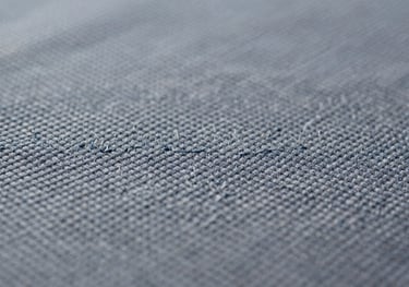 Macro detail of custom embroidery on heavy #4A5568 canvas fabric, showing clean lines and tight stitching.