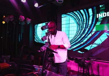 Professional saxophonist performing at London nightclub with vibrant stage lighting and neon backdro