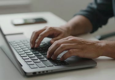 A close-up of a person's hands typing on a high-end keyboard in a stylish, minimalist home office in North America.