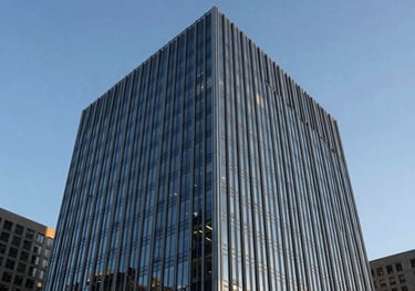 A sleek, modern architectural building made of glass and steel under a clear blue sky in a North American financial district.