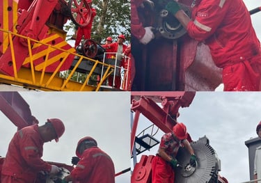 Oil field workers in red uniforms and hard hats perform maintenance on a pumping unit machine.