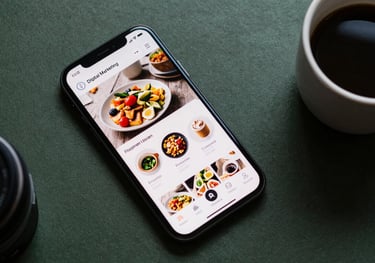 A flat lay of digital marketing tools, a smartphone displaying a social media feed with food photos, and a cup of coffee on a dark green surface.