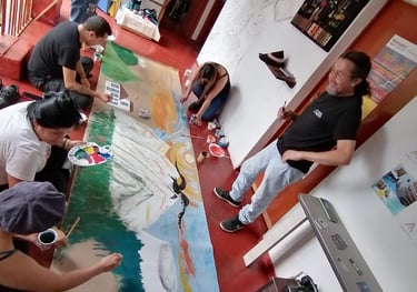 Artistas y estudiantes colaborando en un gran mural comunitario de paisaje en un estudio de arte