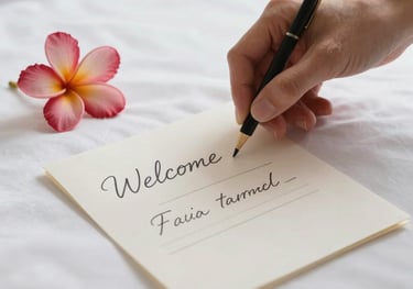 Close-up shot of a hand-written welcome note and a small tropical flower on a crisp white bedsheet in a hotel room. Soft cinematic lighting emphasizing detail and care in service.