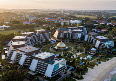 A beautiful drone shot of a beach resort in Indonesia at sunrise. The architecture blends with nature, reflecting a professional management project. The composition is cinematic and serene.