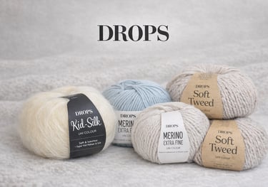 DROPS mezgimo siūlų kamuoliukai ant šviesaus megzto fono.