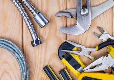 Various plumbing tools are laid out on a wooden table