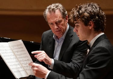A mentor and a young musician discussing sheet music in a professional theater environment in the Pacific Northwest US. Timeless elegance and artistic focus.