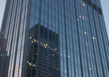 A high-rise glass commercial building facade reflecting the blue hour sky, representing high-value property and corporate assets.
