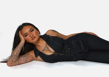 Amelia laying on the ground in a denim jumpsuit with her hand on her head