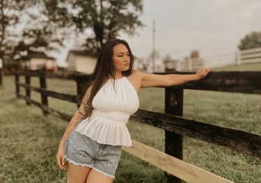 Amelia in a white top posing against a fence