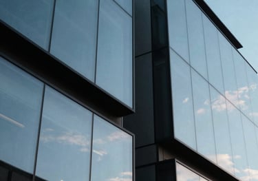 Abstract shot of modern architecture reflecting a sky blue sky, geometric shapes suggesting structure and scale.