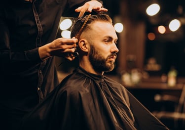 Professional barber giving a stylish fade haircut to a bearded man in a vintage barbershop.