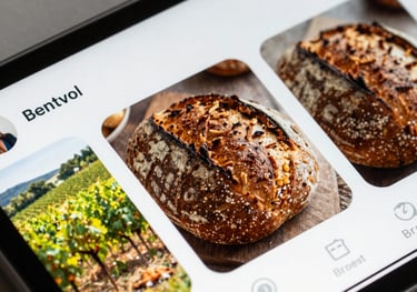 A close-up photograph of a vibrant social media feed displayed on a modern smartphone. The feed shows high-quality photos of rustic sourdough bread and Matte Forest Green vineyards. The lighting is warm and inviting.