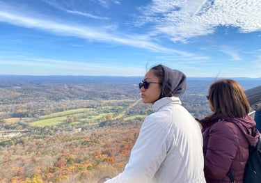 a woman in a white jacket and sunglasses on a mountain