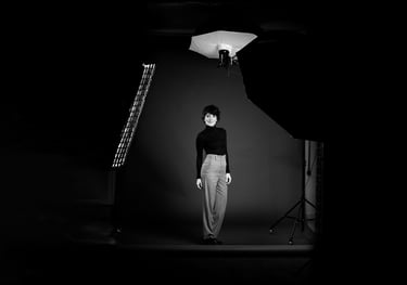 A woman posing for a black and white portrait in a professional photography studio with softbox lighting.