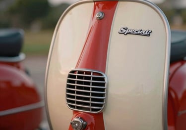 A detailed close-up of a red and cream Lambretta TV, focusing on the specialized engine ventilation and the 'Special' badging. The composition is artistic and nostalgic, shot with a shallow depth of field in a warm Brazilian evening setting.