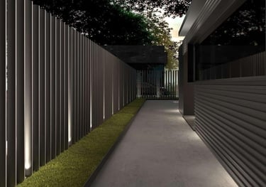 Camino peatonal flanqueado por valla metálica contemporánea con iluminación ambiental