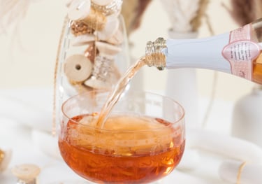 a person pouring a drink into a glass of wine with permanent jewelry chains