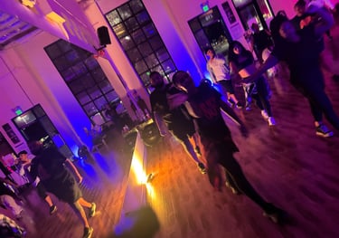 One dancer facing the camera and waving, while another dancer in the back follows.