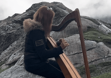 a woman playing a harpet on a rock