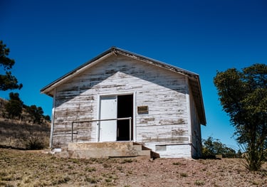 a small, white, distressed house in need of rehabilitation