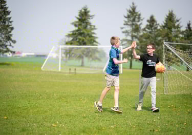 two boys playing soccer in a field