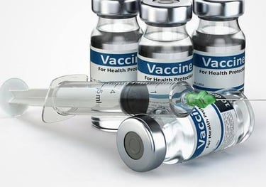 Medical glass vaccine vials with blue labels and a sterile hypodermic syringe for immunization injections.