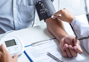 A doctor checking a patient's blood pressure using a digital monitor and stethoscope at a medical clinic.