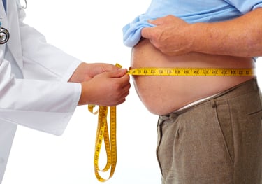 A doctor measuring an overweight man's waist circumference with a yellow tape measure.