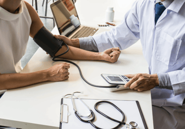 A healthcare professional checking a patient's blood pressure using a digital monitor during a medical consultation.